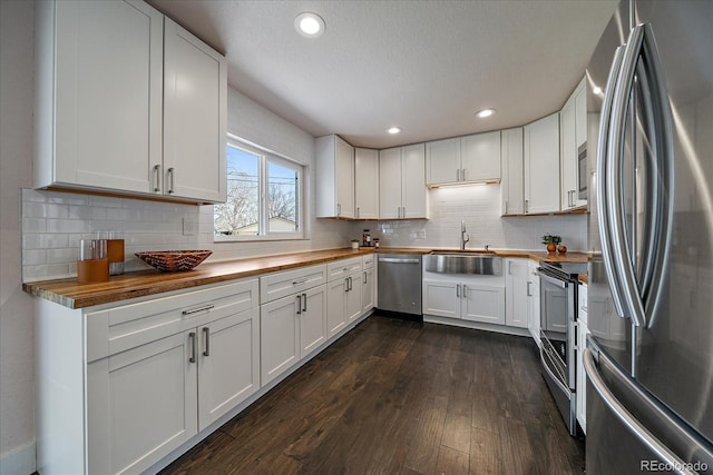 6026 Iris Way, Arvada, CO 80004 - kitchen with butcher block countertops, a sink, decorative backsplash, stainless steel appliances, and dark wood-style floors