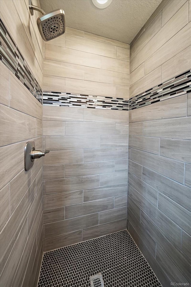 6026 Iris Way, Arvada, CO 80004 - bathroom featuring a textured ceiling and tiled shower