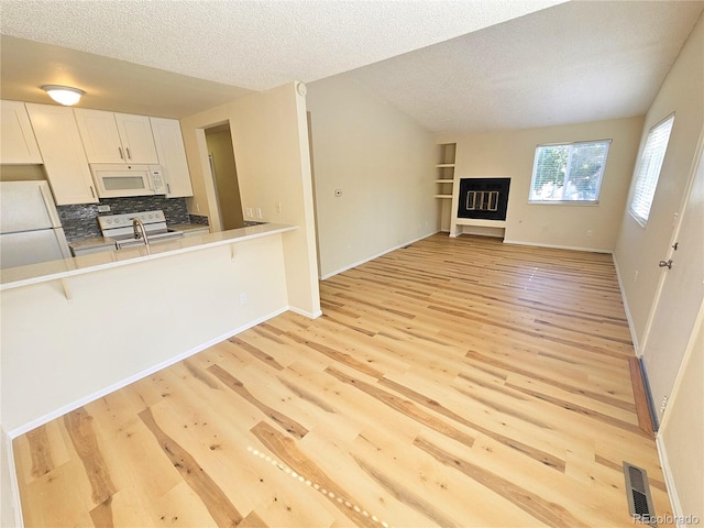 unfurnished living room with a textured ceiling and light hardwood / wood-style flooring