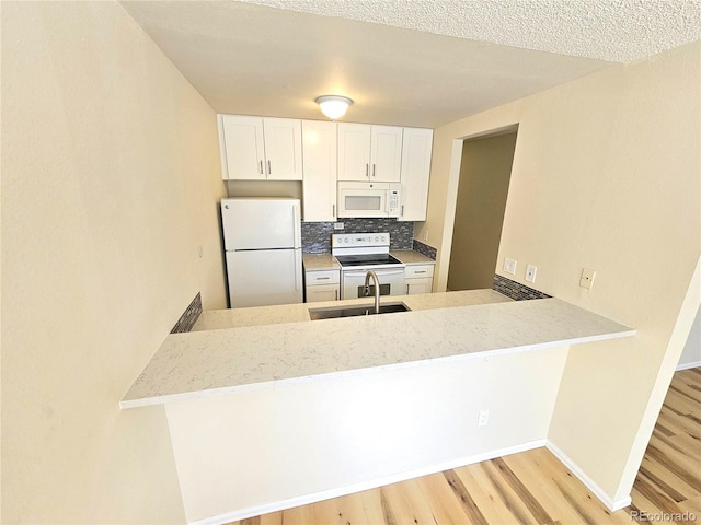 kitchen featuring kitchen peninsula, light wood-type flooring, sink, and white appliances