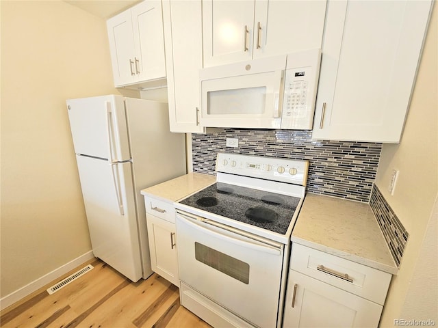 kitchen with light wood-type flooring, white appliances, white cabinetry, light stone counters, and decorative backsplash