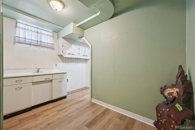 1055 N 18th St, Colorado Springs, CO 80904 - kitchen with light countertops, baseboards, white cabinets, a sink, and light wood-style floors