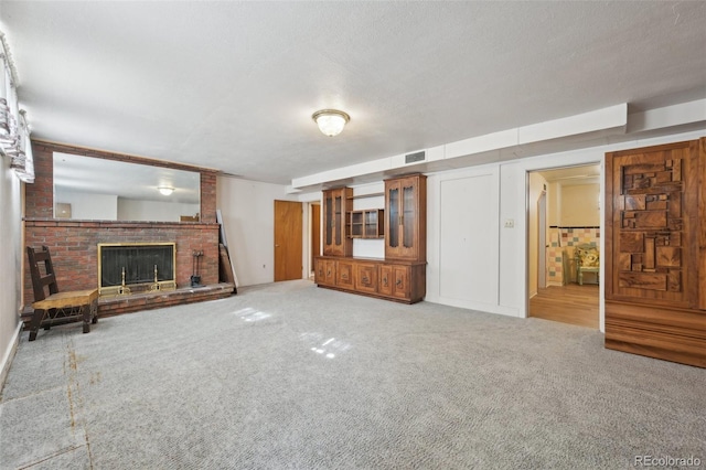 1055 N 18th St, Colorado Springs, CO 80904 - unfurnished living room with carpet, a brick fireplace, a textured ceiling, and visible vents