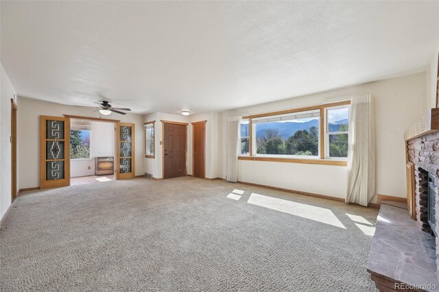 1055 N 18th St, Colorado Springs, CO 80904 - unfurnished living room with light colored carpet, a ceiling fan, a healthy amount of sunlight, and a fireplace