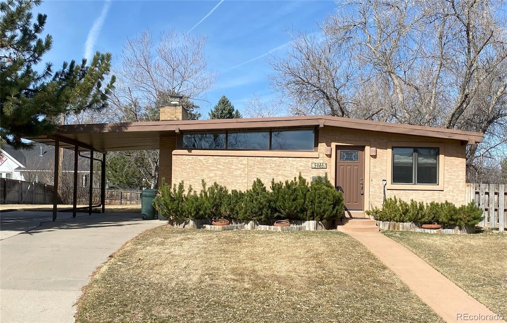 view of front facade featuring a carport, a chimney, and fence