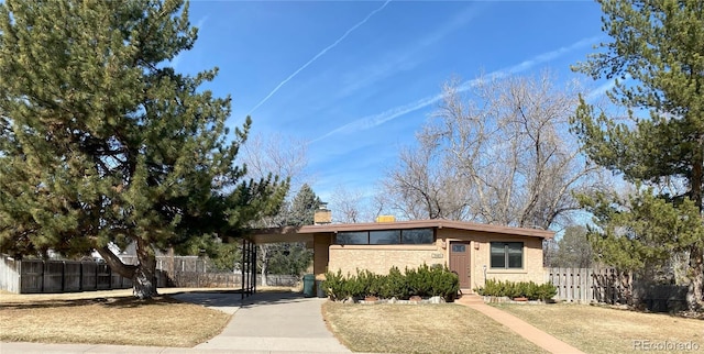 view of front of home with brick siding, a fenced front yard, and a chimney