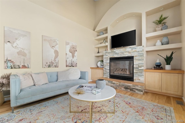 5649 W 109th Cir, Westminster, CO 80020 - living area featuring built in features, light wood-style flooring, a stone fireplace, and lofted ceiling