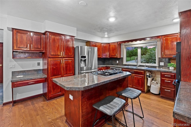 7883 S Espana Way, Centennial, CO 80016 - kitchen featuring stainless steel appliances, a sink, light wood-style flooring, and a center island