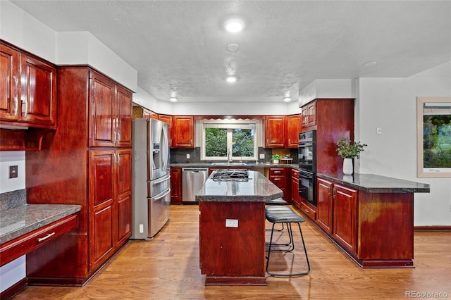 7883 S Espana Way, Centennial, CO 80016 - kitchen with stainless steel appliances, dark brown cabinets, a peninsula, a breakfast bar, and light wood-type flooring