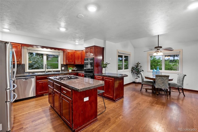 7883 S Espana Way, Centennial, CO 80016 - kitchen featuring appliances with stainless steel finishes, a center island, a sink, dark countertops, and dark brown cabinets