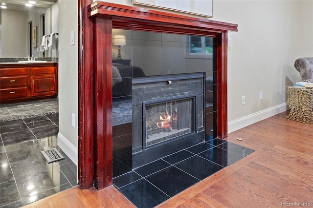 7883 S Espana Way, Centennial, CO 80016 - detailed view of baseboards, a fireplace with flush hearth, a sink, and wood finished floors
