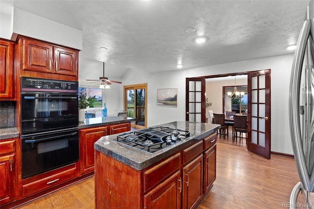 7883 S Espana Way, Centennial, CO 80016 - kitchen with black appliances, light wood finished floors, dark countertops, a textured ceiling, and a chandelier