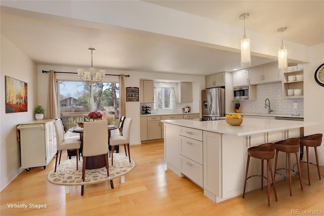 3785 S Benton Way, Denver, CO 80235 - kitchen with appliances with stainless steel finishes, tasteful backsplash, a chandelier, light countertops, and light wood-style flooring