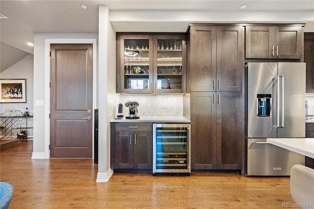 bar featuring high end fridge, a dry bar, light wood-style floors, wine cooler, and backsplash