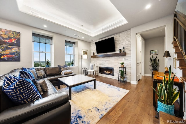 living room featuring a raised ceiling, a fireplace, recessed lighting, visible vents, and hardwood / wood-style flooring