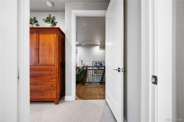 hallway with light carpet and an upstairs landing