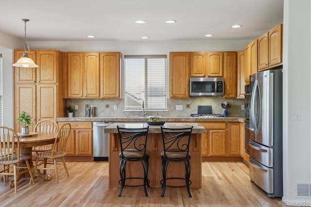 10448 Kicking Horse Dr, Littleton, CO 80125 - kitchen featuring appliances with stainless steel finishes, light wood-type flooring, a kitchen island, tasteful backsplash, and recessed lighting