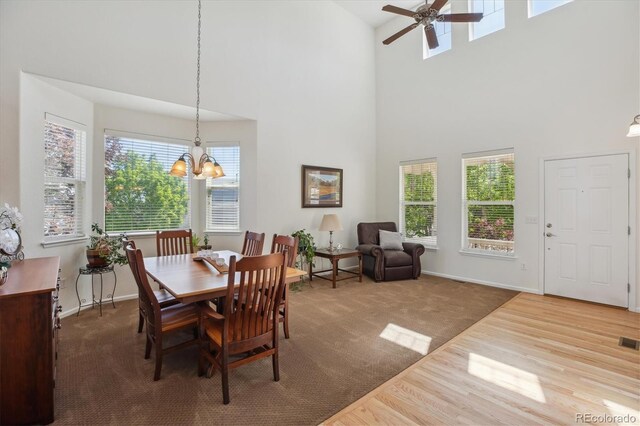 10448 Kicking Horse Dr, Littleton, CO 80125 - dining area featuring a towering ceiling, a chandelier, a ceiling fan, baseboards, and wood finished floors