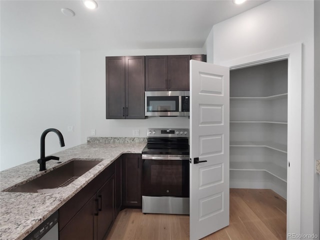 0125 W Keystone Rd Unit 209, Keystone, CO 80435 - kitchen with stainless steel appliances, a sink, light wood-type flooring, dark brown cabinetry, and light stone countertops