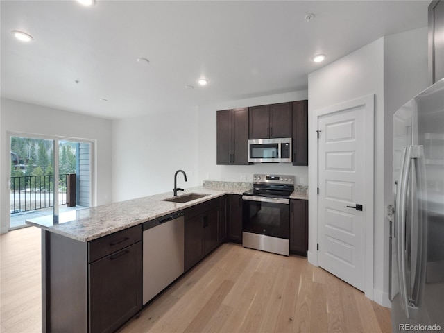 0125 W Keystone Rd Unit 209, Keystone, CO 80435 - kitchen with stainless steel appliances, a sink, a peninsula, light wood finished floors, and dark brown cabinets