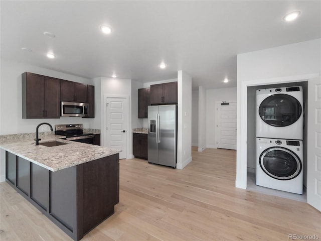 0125 W Keystone Rd Unit 209, Keystone, CO 80435 - kitchen featuring stainless steel appliances, stacked washer and clothes dryer, a sink, a peninsula, and light wood finished floors