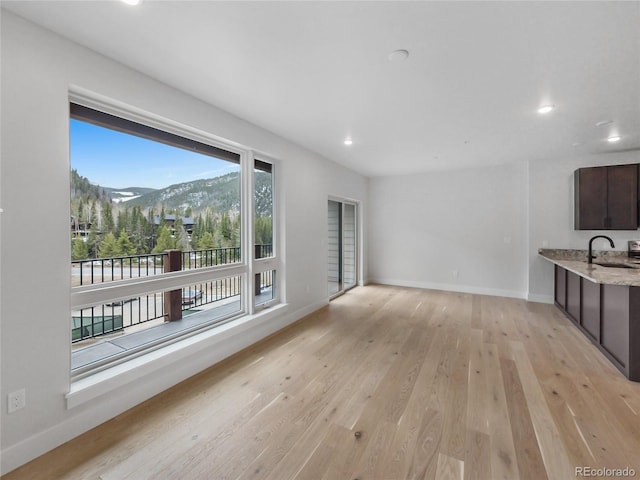 0125 W Keystone Rd Unit 209, Keystone, CO 80435 - unfurnished living room with light wood finished floors, a mountain view, recessed lighting, baseboards, and a sink