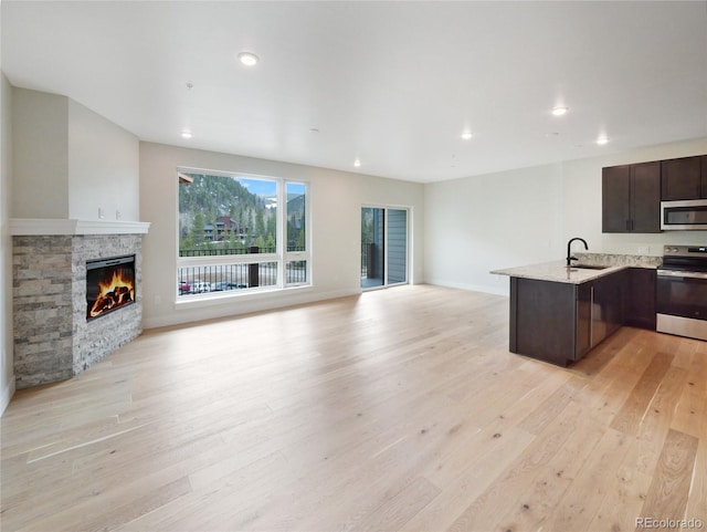 0125 W Keystone Rd Unit 209, Keystone, CO 80435 - kitchen with appliances with stainless steel finishes, open floor plan, a sink, dark brown cabinetry, and light wood-style floors