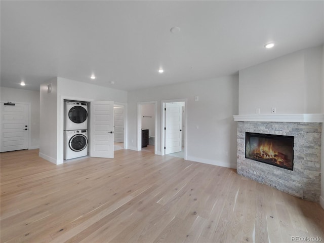 0125 W Keystone Rd Unit 209, Keystone, CO 80435 - unfurnished living room featuring stacked washer / drying machine, a fireplace, light wood-type flooring, recessed lighting, and baseboards