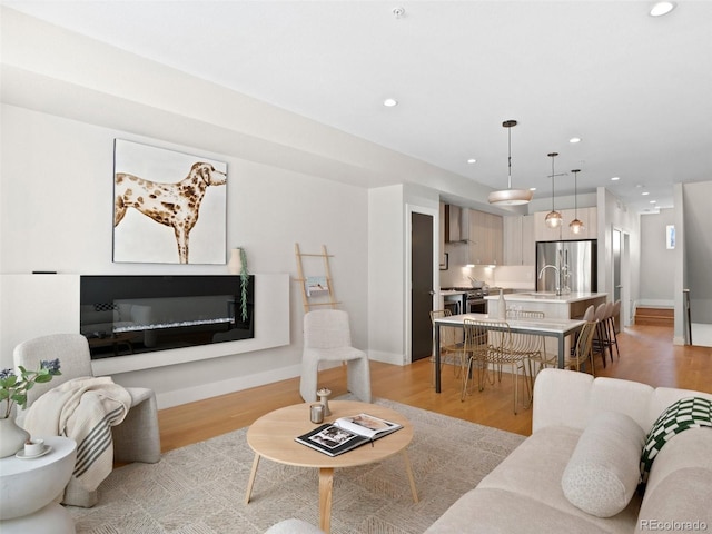 living room featuring recessed lighting, baseboards, and light wood-type flooring