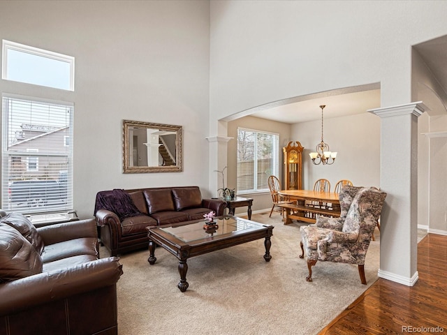 living room with a notable chandelier, baseboards, ornate columns, arched walkways, and wood finished floors