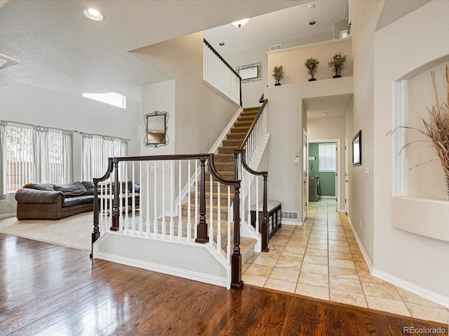 staircase with visible vents, baseboards, a textured ceiling, and wood finished floors