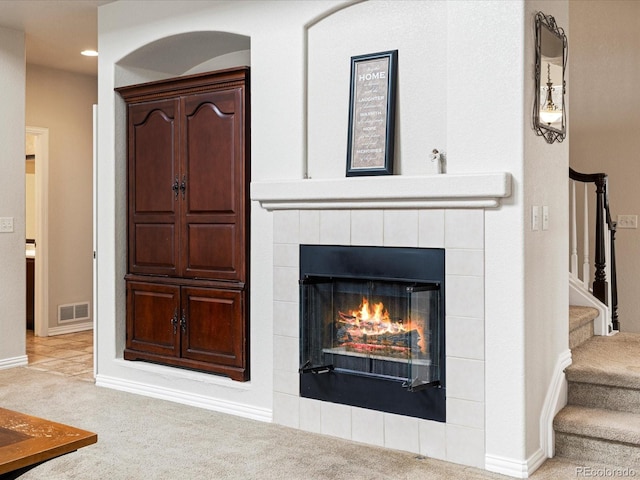 interior details featuring a tiled fireplace, visible vents, baseboards, and carpet flooring