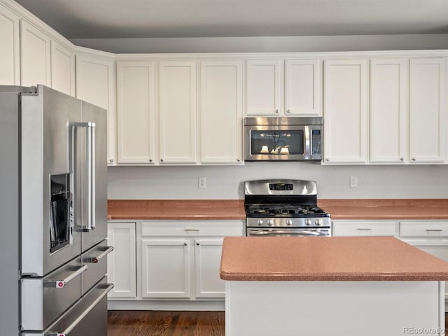 kitchen with stainless steel appliances, white cabinets, a center island, and dark wood finished floors