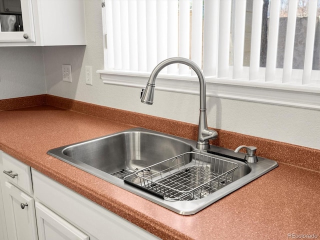 interior details with a sink, glass insert cabinets, and white cabinets