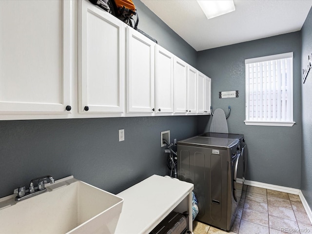 laundry room featuring light tile patterned floors, cabinet space, a sink, baseboards, and washing machine and dryer