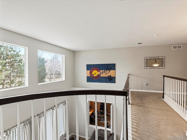 hall featuring visible vents, baseboards, and carpet