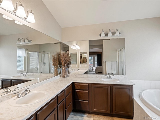 bathroom featuring double vanity, a bath, a sink, and a stall shower