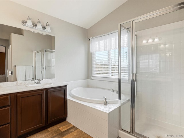bathroom featuring a shower stall, vanity, wood finished floors, vaulted ceiling, and a garden tub