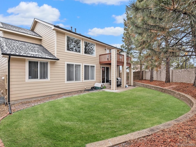 rear view of house featuring a lawn, a patio, a wooden deck, fence private yard, and roof with shingles