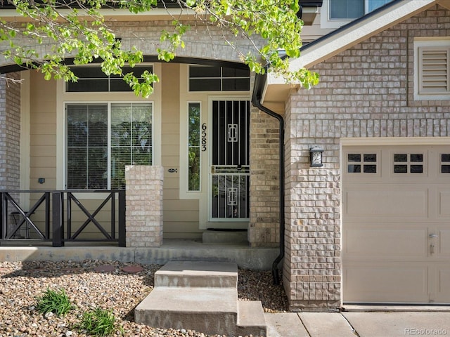 view of exterior entry featuring a porch and brick siding
