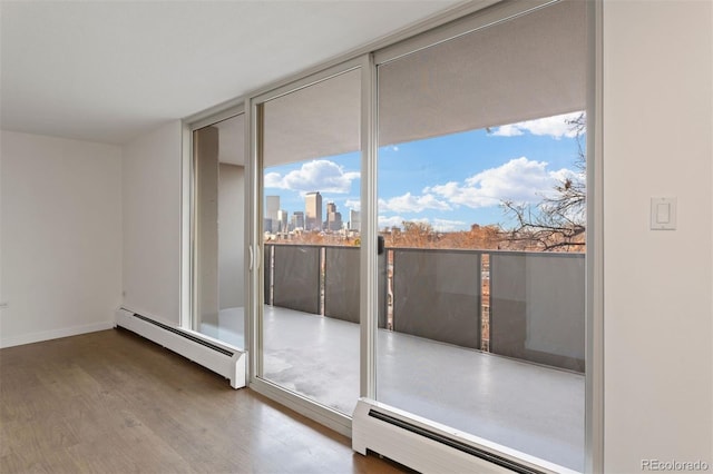 interior space featuring hardwood / wood-style floors, plenty of natural light, expansive windows, and a baseboard heating unit