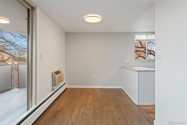 interior space featuring an AC wall unit, a baseboard radiator, and wood-type flooring