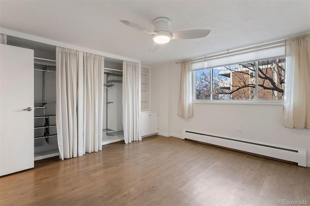 unfurnished bedroom with hardwood / wood-style floors, a baseboard radiator, and ceiling fan