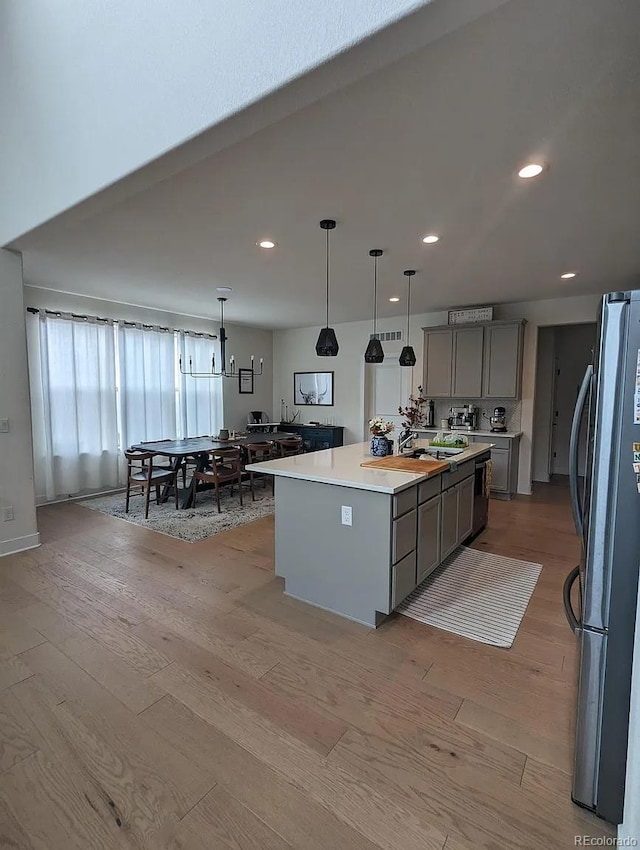 6332 E 142nd Pl, Thornton, CO 80602 - kitchen with freestanding refrigerator, gray cabinets, light wood-style flooring, light countertops, and a center island