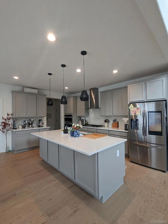 6332 E 142nd Pl, Thornton, CO 80602 - kitchen featuring appliances with stainless steel finishes, gray cabinetry, wall chimney range hood, decorative backsplash, and light wood finished floors