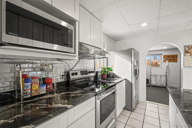 kitchen featuring extractor fan, appliances with stainless steel finishes, a paneled ceiling, white cabinetry, and dark stone countertops