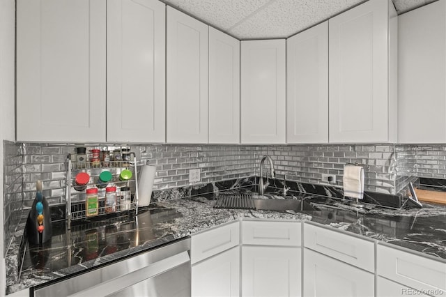 kitchen with sink, white cabinetry, a paneled ceiling, dark stone countertops, and stainless steel dishwasher