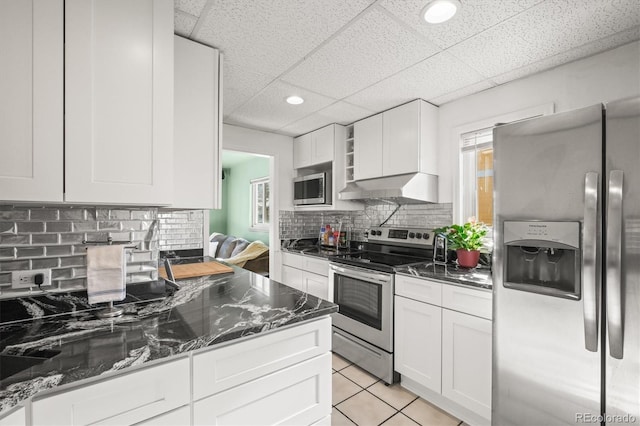 kitchen with stainless steel appliances, white cabinetry, dark stone countertops, and a paneled ceiling