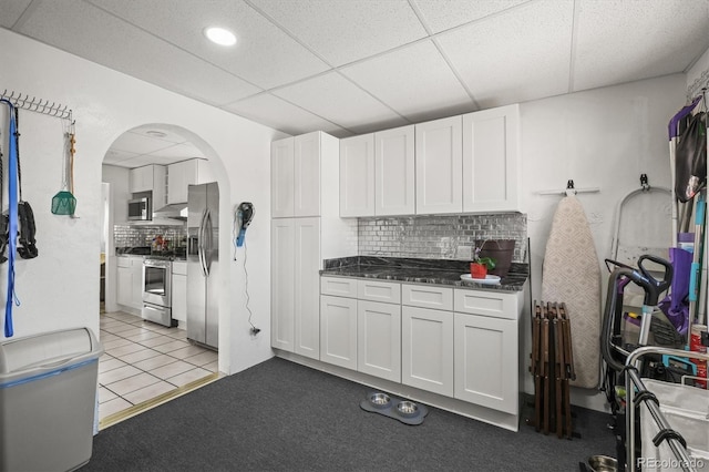 kitchen with a drop ceiling, decorative backsplash, white cabinets, and appliances with stainless steel finishes