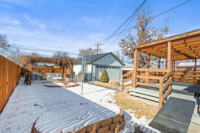 yard layered in snow with a wooden deck, a garage, and an outdoor structure